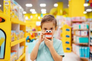 boy-holds-jaw-toy-at-the-shelf-in-kids-store